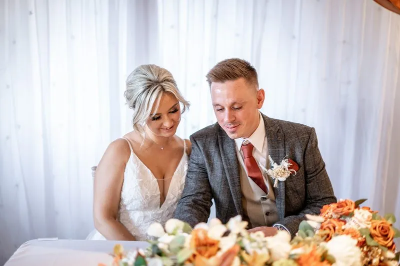 Bride and groom outside the church, surrounded by autumn colour